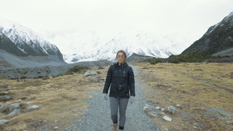 un frente en la siguiente foto de una mujer caminando entre montañas nevadas en una fría mañana de invierno en nueva zelanda