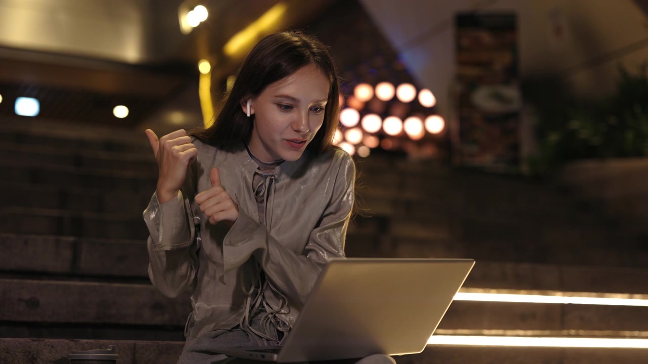 Giovane donna in videochiamata sul laptop all'aperto di notte