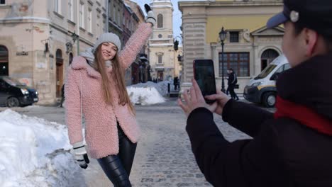 Dos-Jóvenes-Mujeres-Sonrientes-Bloggers-Viajeras-Tomando-Fotos-De-Retratos-En-Teléfonos-Móviles-En-Las-Calles-De-La-Ciudad