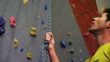 hombre sosteniendo una cuerda cerca de una pared artificial 4k