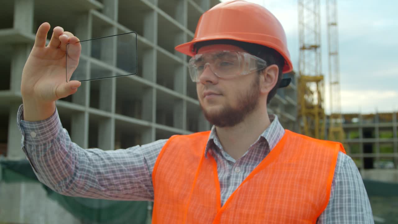 Architect or Engineer using smartphone transparent hologram digital display applicatiion in front of building under construction. Technology, people.