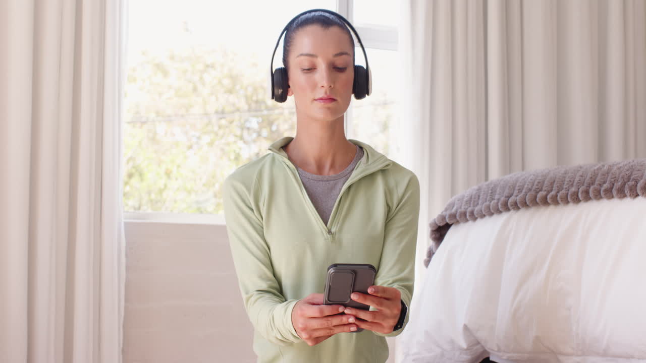 Woman wearing headphones relaxing at home, enjoying peaceful moment by window