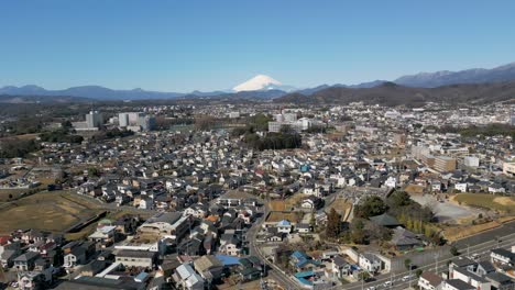 un avión no tripulado cinematográfico se inclina sobre el suburbio de tokio con el nevado monte fuji en la distancia