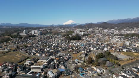 cinematic drone tilt up over tokyo suburb with snowy mount fuji in distance