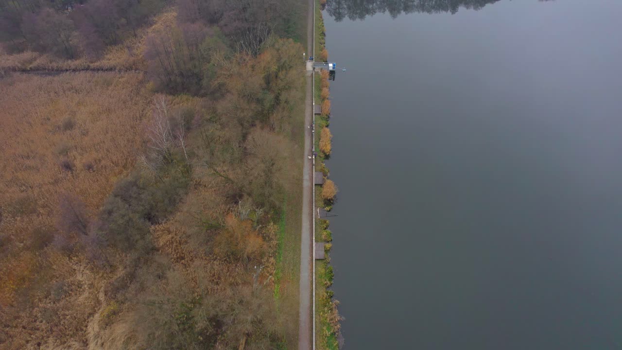 추운 아침, 나무와 풀이 있는 자연 풍경이 있는 가을의 고요한 호수 기슭에 어부들이 있는 길