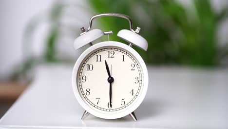 las agujas en el dial del despertador blanco se mueven rápido.