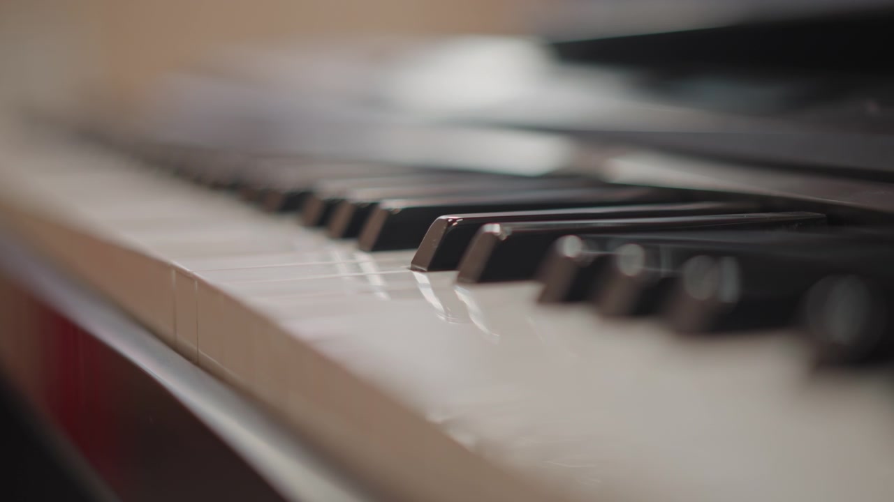 Close up piano keys during practice. Soft natural light and shallow depth of field highlight ivory and ebony texture, subtle fingertip motion and key wear evokes focused student rehearsal, teacher