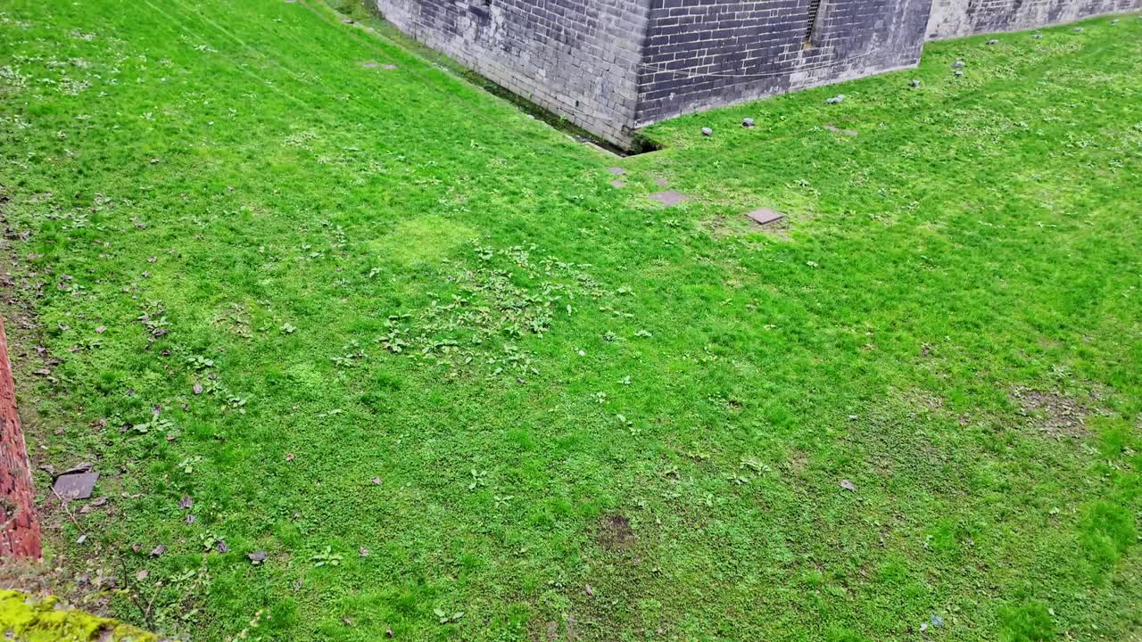 Historic castle in Milan with brick walls and green lawn surrounding it