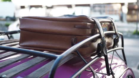 suitcase on a roof rack of a vintage purple car