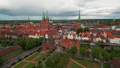 aerial shot around lubeck city center with the holstentor gothic gate in the foreground and the city center with churches in the background, lubeck city, schleswig-holstein land, germany