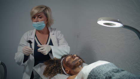 beautician applying carbon mask in wellness clinic. facial skin rejuvenation