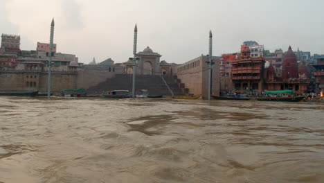 cinematic ganges still calm muddy brown river cruise chowk canal boat varanasi northern india state ancient holy city khidkiya ghat pradesh provinc landscape gray cloudy afternoon follow motion right