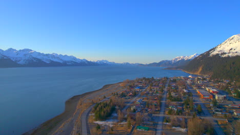 Seitliche-Luftaufnahme-Der-Innenstadt-Von-Seward,-Alaska-Und-Der-Berge-Bei-Sonnenaufgang