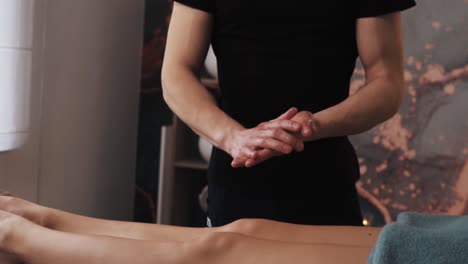 Masseur-Reibt-Vor-Dem-Eingriff-Massageöl-Vor-Dem-Hintergrund-Schöner-Weiblicher-Beine-Ein