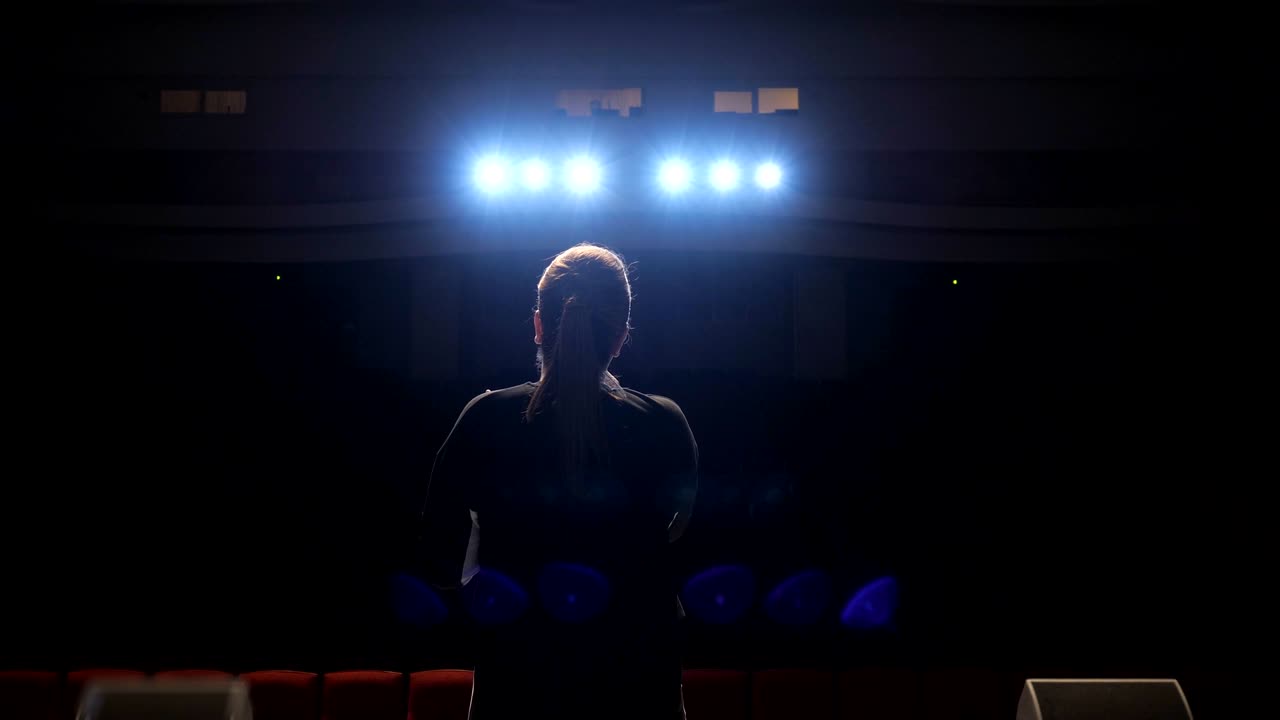 la niña irreconocible cantando en el escenario frente a los reflectores