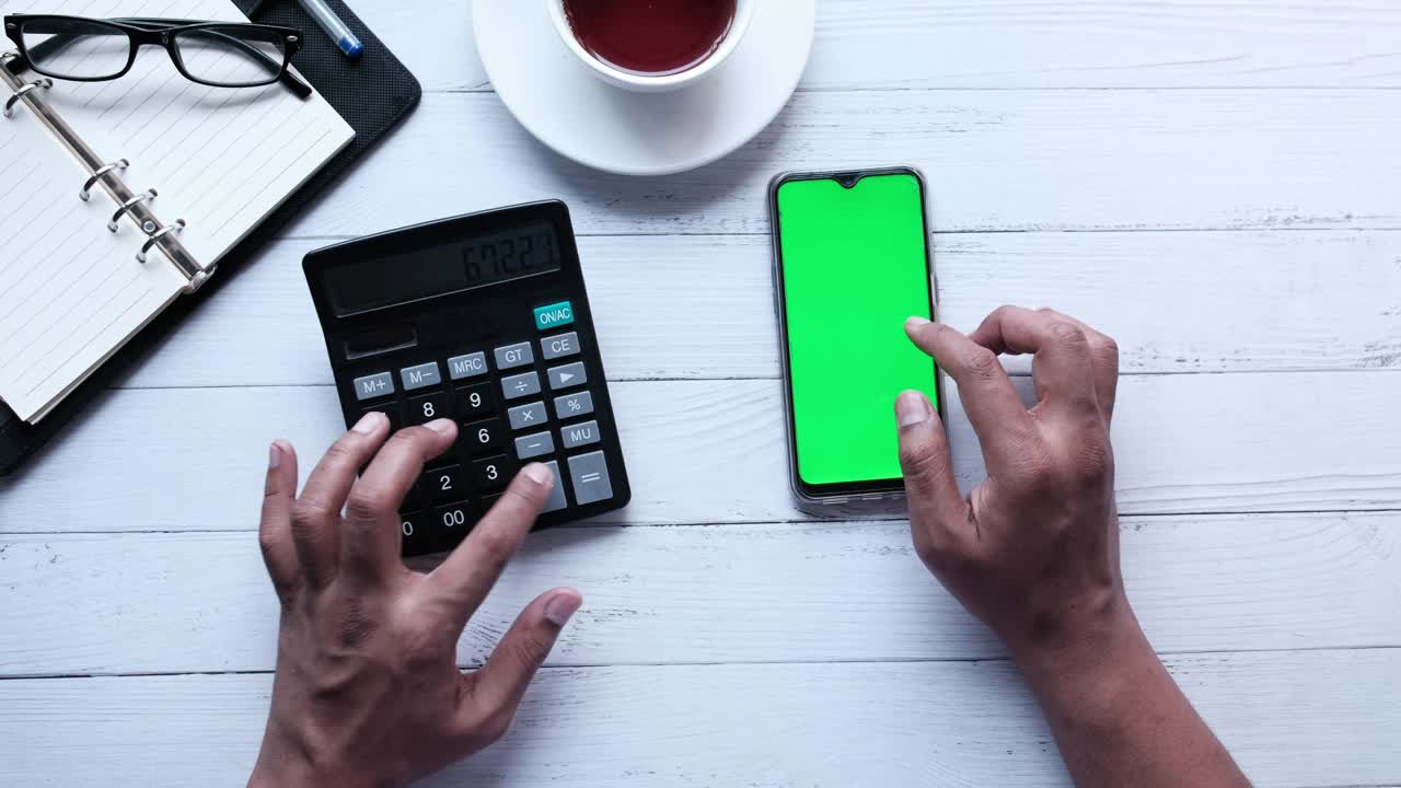 person using smart phone with green screen and counting on calculator