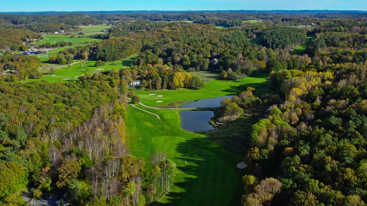 Dronebeeld van Kungsbacka Golfclub met groene fairways, vredig meer, bos en schilderachtig landschap tijdens een zonnige dag in Halland, Zweden