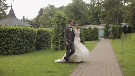 Lovely-newlyweds-caucasian-bride-groom-walking-in-park,-holding-hands,-wedding-couple-family