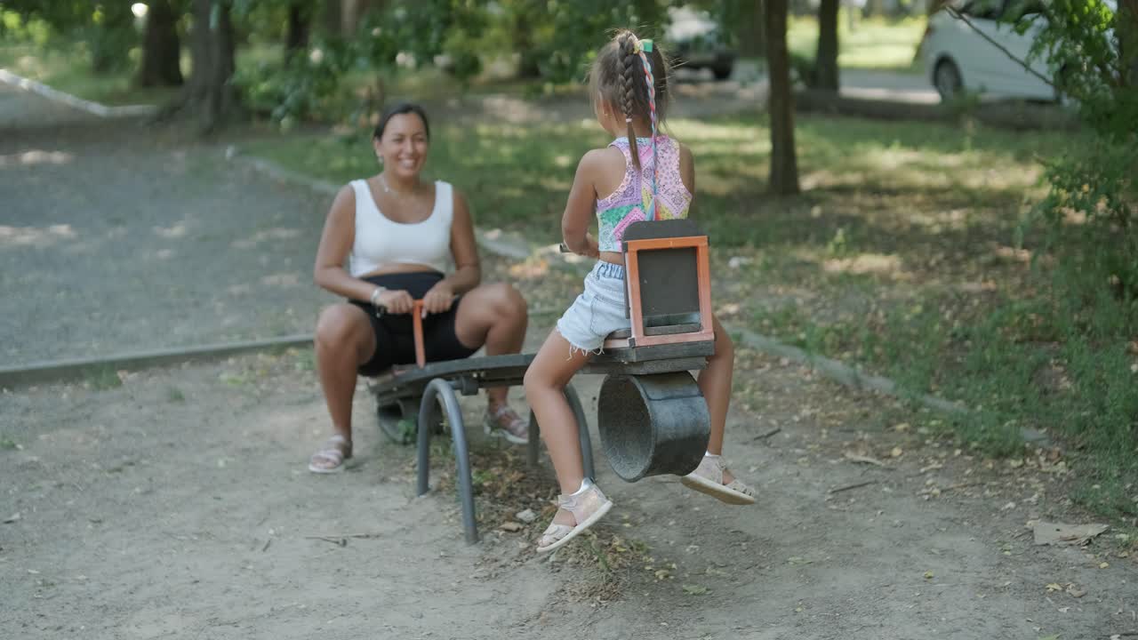 madre y hija embarazadas jugando en el columpio en el parque