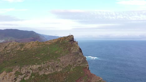 drone shot over the cliff of a peninsula in madeira with a small watch tower or lighthouse on the top