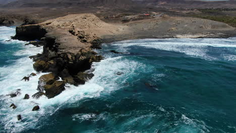 vista aérea en un círculo sobre la playa de la pared y la formación rocosa que está allí, en la isla de fuerteventura en un día soleado