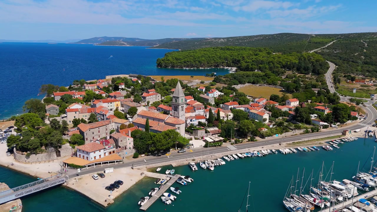 Panorama della città di Osor sull'isola di Cherso, Croazia, in una splendida giornata estiva. Le viste aeree mostrano il centro storico, spiagge soleggiate, yacht a vela, il porto turistico e campeggi vicini sulla costa adriatica mediterranea