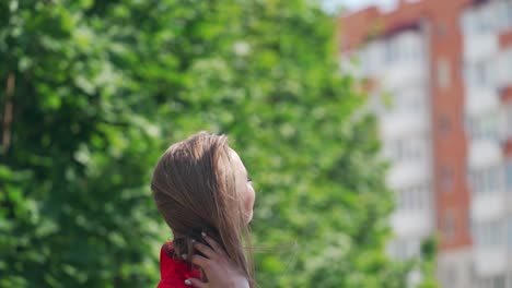 beautiful smiling woman with long hair. portrait of a gorgeous model in red clothing on green tree background. happy attractive female outdoors.