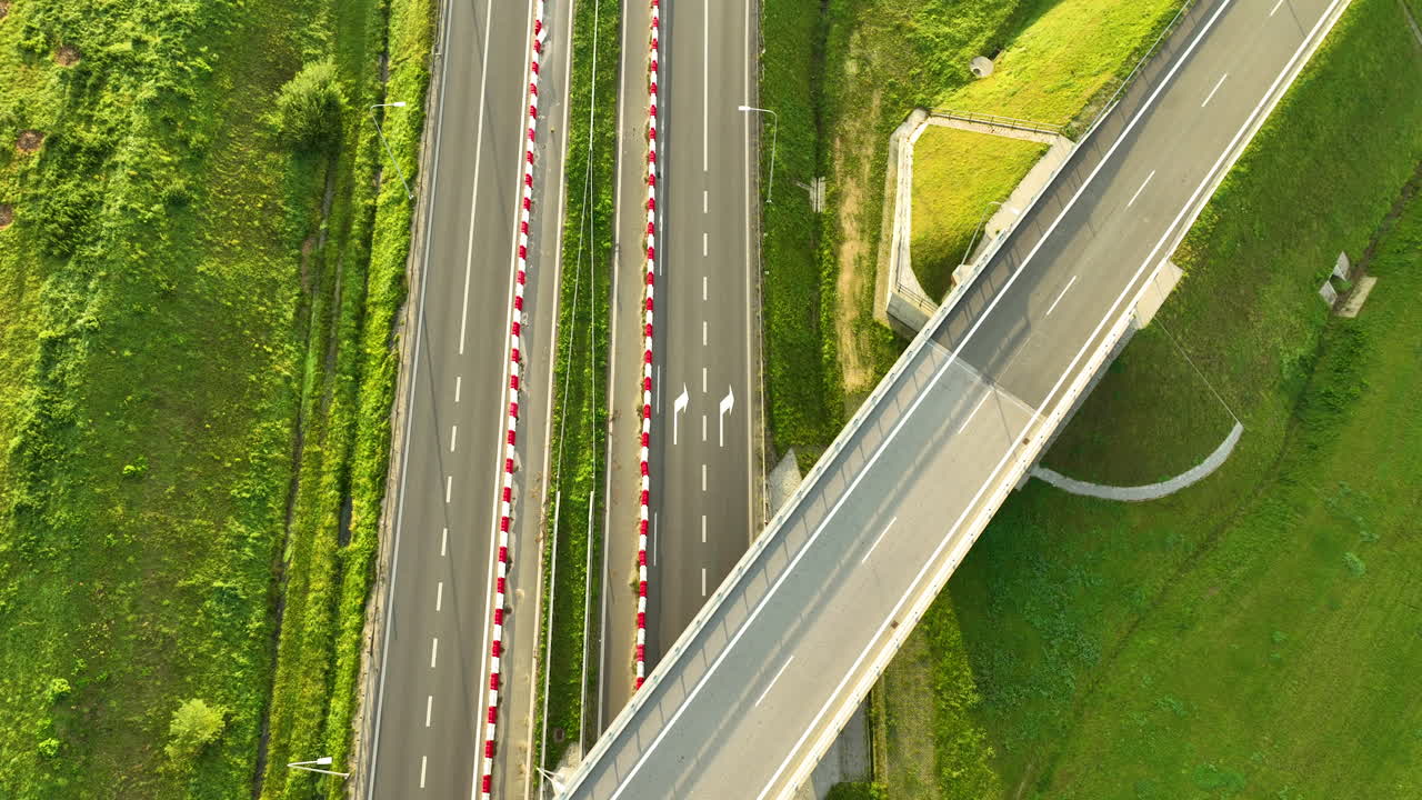 Top-down aerial view capturing the geometric layout of a modern highway overpass and the lanes of the S6 expressway, bordered by red and white safety barriers