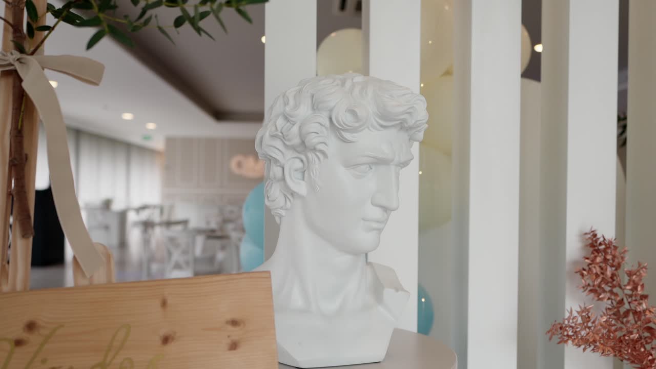 White plaster bust sculpture placed near modern white vertical slats in a bright interior space