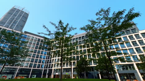 urban design in green space. buildings with glass facades surround a lush green area under a clear blue sky, showcasing a thriving urban environment