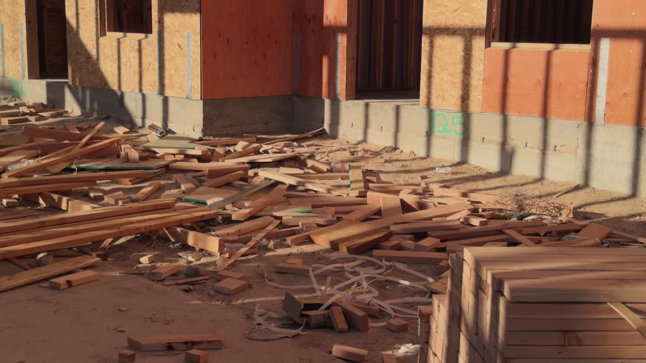 Slow panning view of wood scrap and building base on busy jobsite