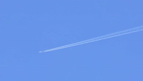 a jet aircraft leaves a distinct contrail against a bright blue sky, showcasing high-altitude flight.