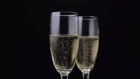 two glass of champagne with a rotating bubbles inside black background close up two glass of champagne with a rotating bubbles inside the foam are disappearing and rising up black background close up
