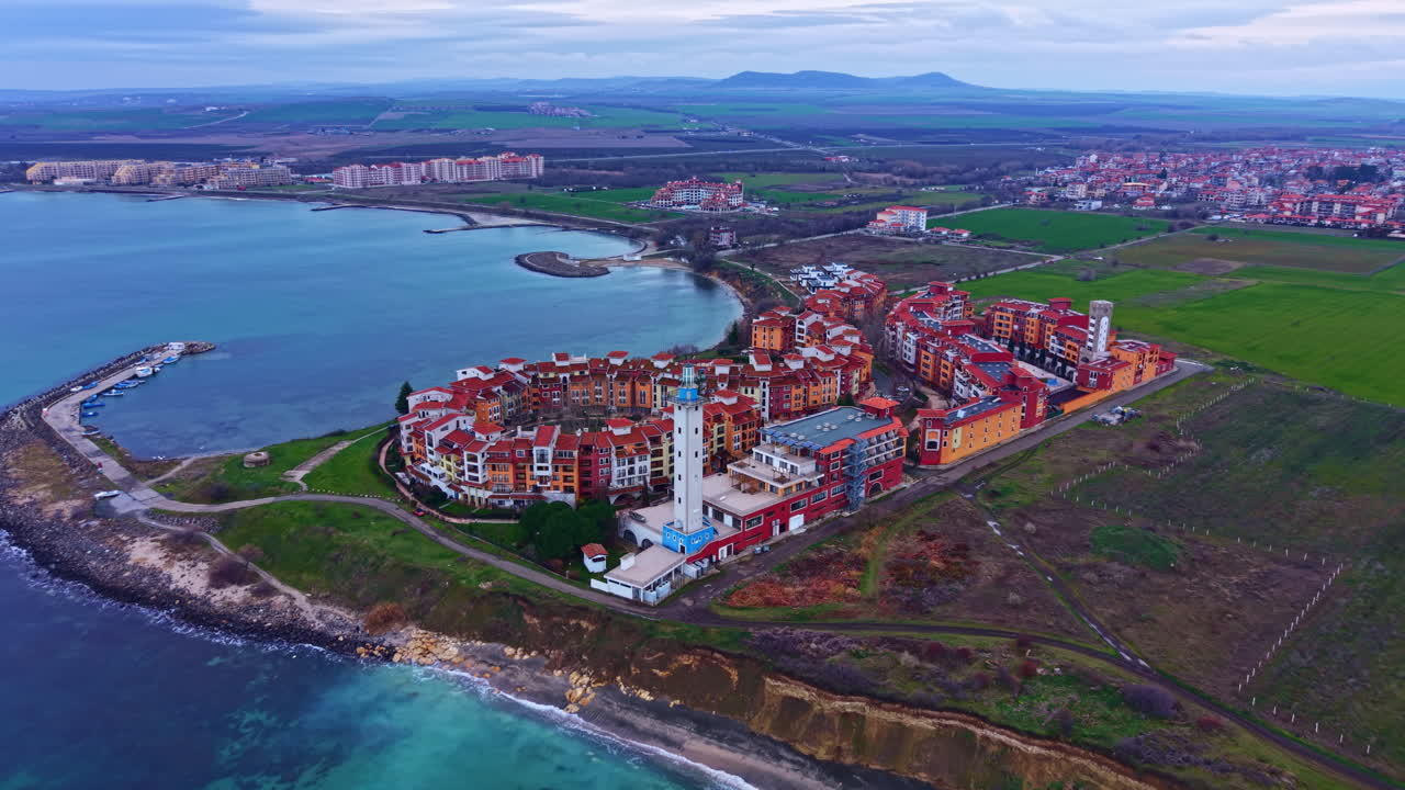 Sviluppo costiero con edifici, coste e campi vicino a uno specchio d'acqua in una zona rurale con colline sullo sfondo durante il giorno
