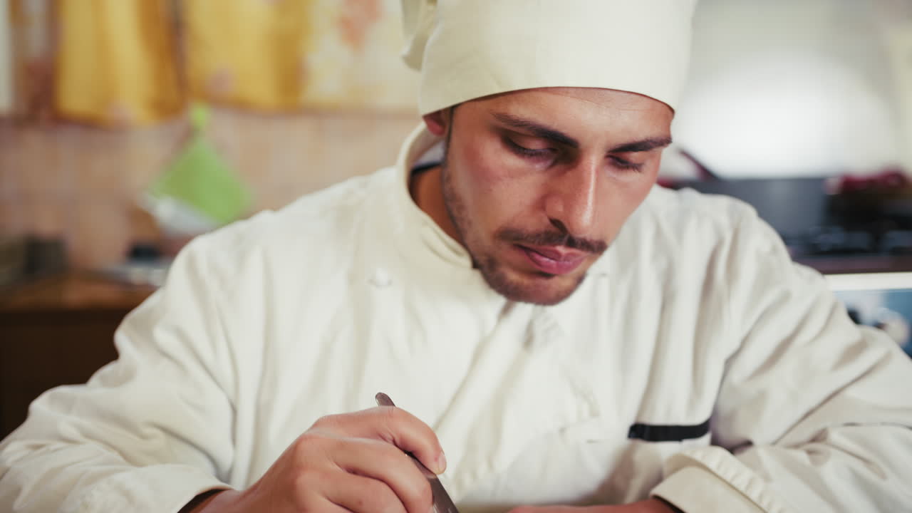 Male Chef In Uniform Tastes His Dishes Before Serving Diners In The Kitchen