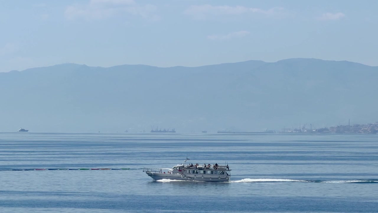 Perahu Penumpang dan Perahu Motor Melaju di Laut Biru Tenang dengan Pegunungan di Latar Belakang