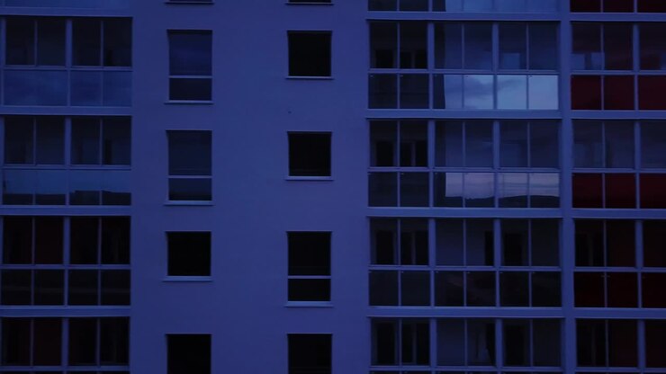 Vista drone di un moderno condominio con facciata colorata, finestre e balconi. Riprese aeree di un edificio residenziale di notte.