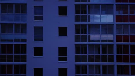 drone view of colorful facade contemporary apartment building, windows and balconies. aerial footage highrise estate at night time.