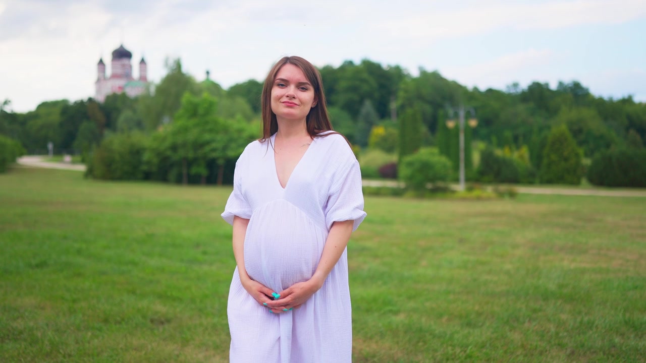 Happy Pregnant Woman Standing in a Green Park