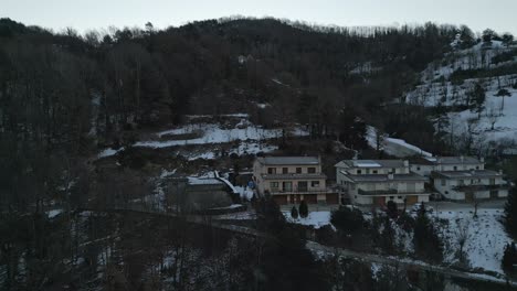 aerial drone fly above ribes de freser pyrenees town in snowy winter, houses, hills, neighborhood and dry pine trees cloudy panorama, girona, catalonia, spain