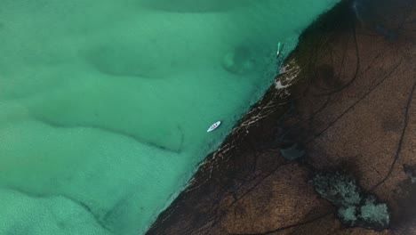 aerial top down orbit of boat in waters of sussex inlet, nsw, australia, winding estuaries surrounded by lush greenery