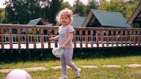 tracking little cute baby runs around lawn and kicks the ball