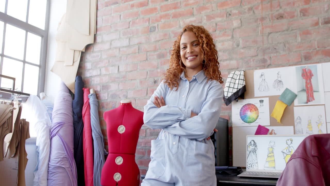 Portræt af glad biracial kvindelig modedesigner, der smiler i studie, kopiplads, slowmotion