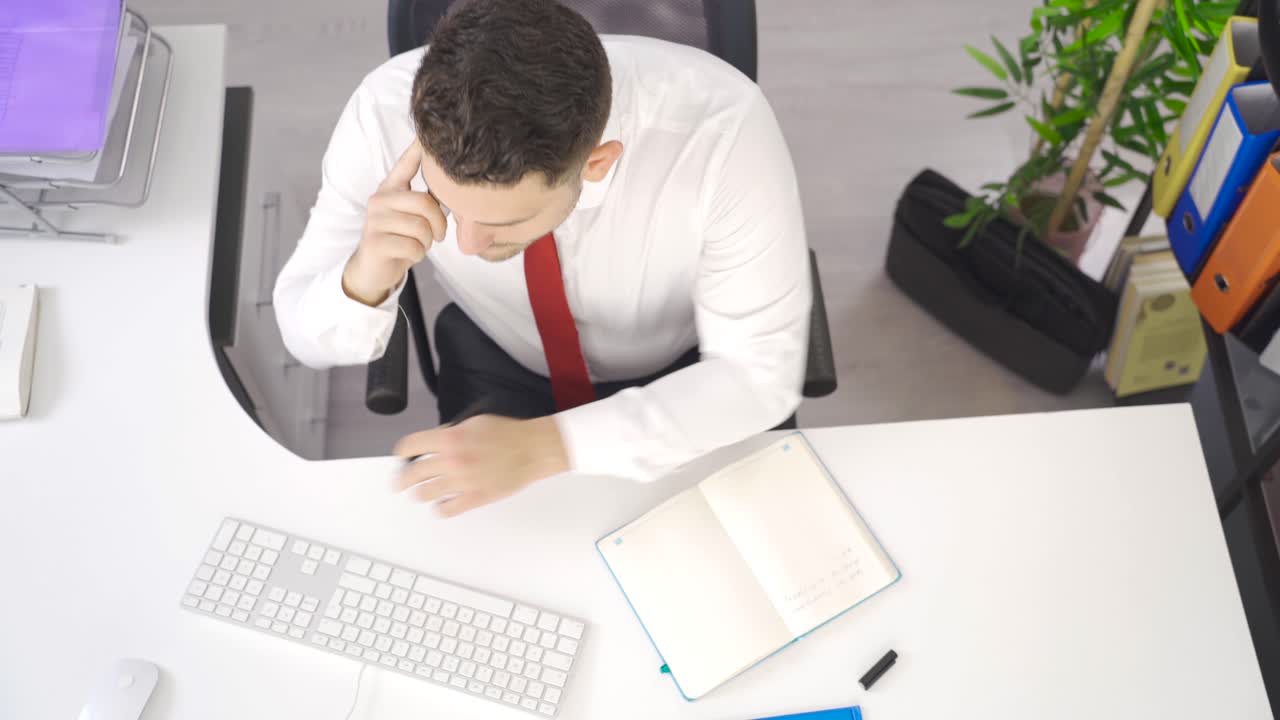 비즈니스맨이 사무실에서 전화로 이야기하고 노트북에 메모를 쓰고 있습니다.