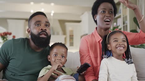 Excited-african-american-parents-with-son-and-daughter-watching-sport-on-tv-at-home,-slow-motion