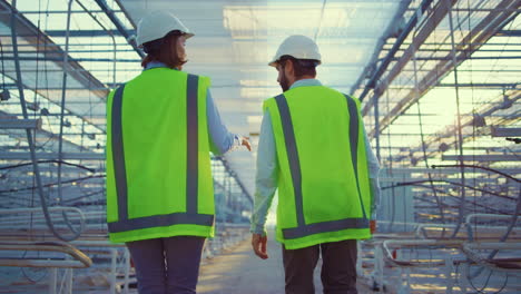 empty manufacture workers walking among glasshouse devices wearing green uniform
