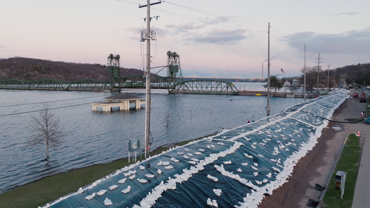 Large sandbag barrier and sump pumps along river preventing high water from flooding city
