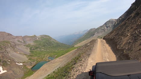 Rooftop-view-of-driving-on-narrow-Black-Bear-Pass-trail-cut-into-a-steep-and-rock-mountainside-high-above-Mineral-Creek-near-Telluride-Colorado