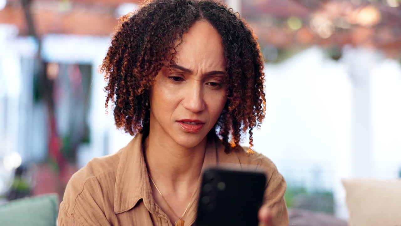 A woman looking at her smartphone with a concerned expression