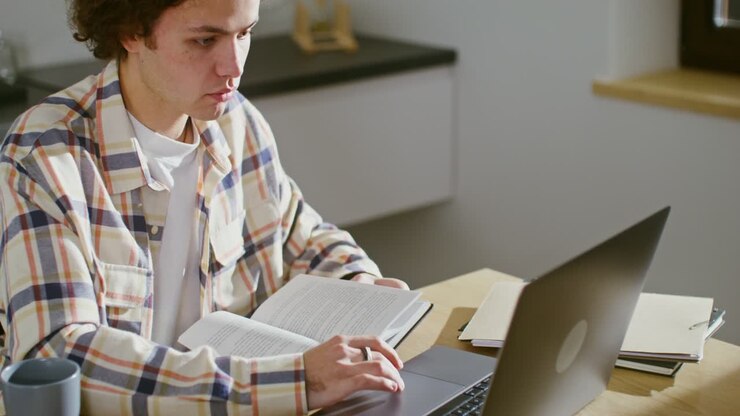Ung person studerer med laptop og bøger